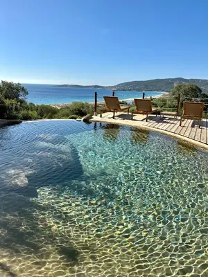 a swimming pool with two chairs in the water at Tour Génoise Micalona, Domaine de l'Oglisatru in Olmeto