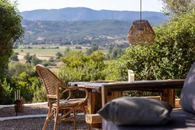 a wooden table and chairs with a view of the mountains at Tour Génoise Micalona, Domaine de l'Oglisatru in Olmeto