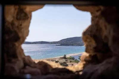 a view of a beach through a window at Tour Génoise Micalona, Domaine de l'Oglisatru in Olmeto