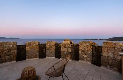 a patio with chairs and the ocean in the background at Tour Génoise Micalona, Domaine de l'Oglisatru in Olmeto