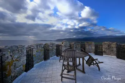 a table and chairs sitting on a patio overlooking the water at Tour Génoise Micalona, Domaine de l'Oglisatru in Olmeto