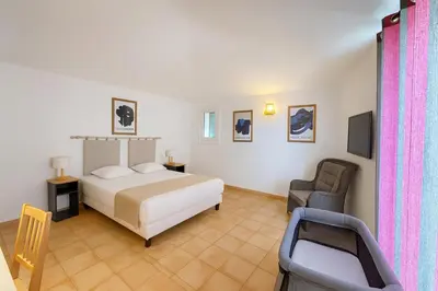 a bedroom with a bed and a chair and a television at La Veglia in Porto-Vecchio