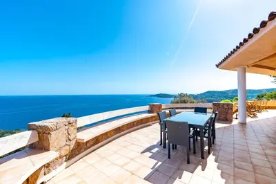 a patio with a table and chairs and the ocean at La Veglia in Porto-Vecchio