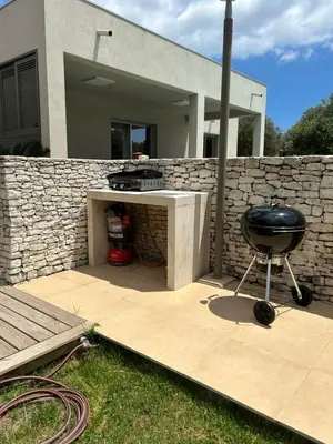 a grill on a patio with a stone wall at La villa Serena in Bonifacio