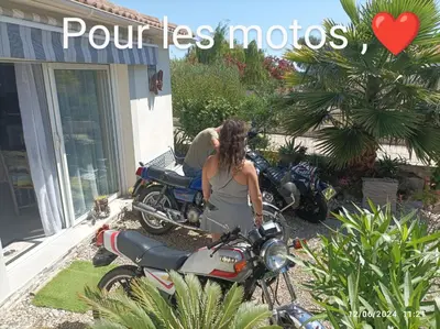 a woman sitting on a motorcycle in front of a house at CASA Piana in Cervione