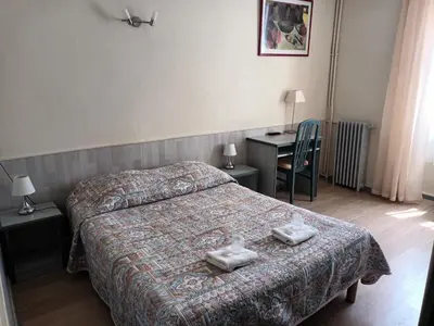 a hotel room with a bed and a desk at Hotel de La Paix in Corte