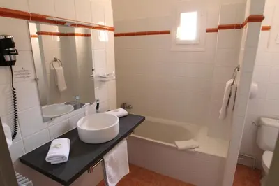 a bathroom with a sink and a tub and a toilet at Hotel de La Paix in Corte
