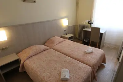 a hotel room with two beds and a table at Hotel de La Paix in Corte