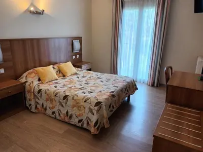 a hotel room with a bed and a desk at Hotel de La Paix in Corte