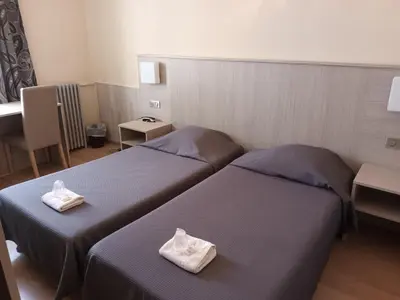 two beds in a hotel room with towels on them at Hotel de La Paix in Corte