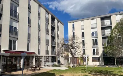 two large white buildings with a picnic table in a courtyard at Appart Hotel Corte HR in Corte