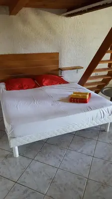 a large white bed with red pillows on it at English Club in Corsica A in Porri