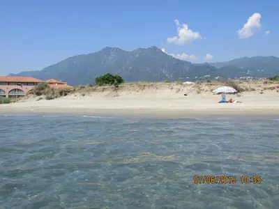 a beach with a person sitting under an umbrella at Hotel Costa Verde in Moriani Plage