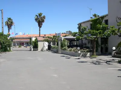 an empty street with palm trees and a building at Hotel Costa Verde in Moriani Plage