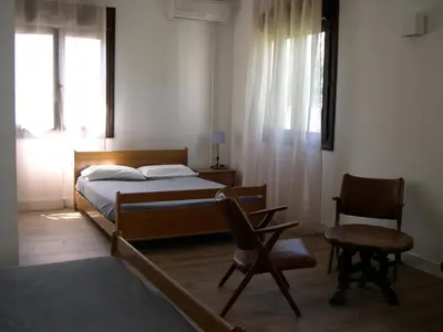 a bedroom with a bed and a chair and window at Hotel Costa Verde in Moriani Plage