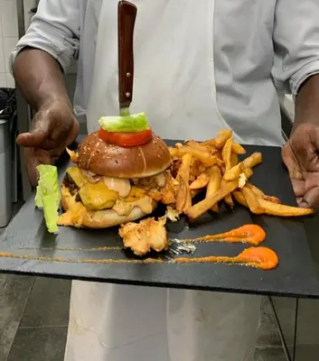 a chef holding a plate with a sandwich and french fries at Mariana Plage in La Marana