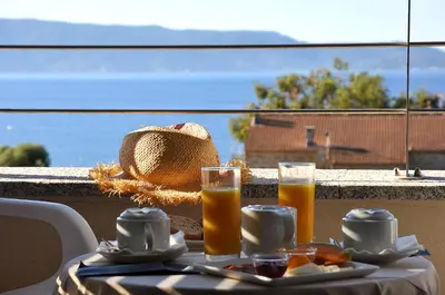 a table with two glasses of orange juice and a hat at Hotel Les Eucalyptus in Porto Pollo