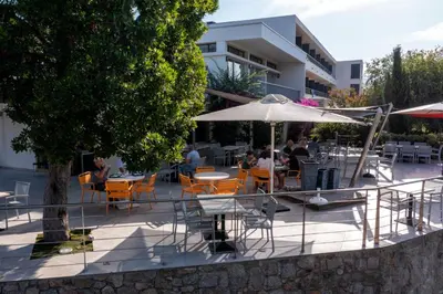 a group of people sitting at tables with an umbrella at Hotel Les Eucalyptus in Porto Pollo