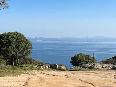 a cross on a hill next to a body of water at Gîte à Poggiale de Figari in Figari