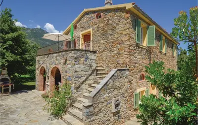 a stone building with a staircase and an umbrella at Awesome Home In Santa Maria Poggio in Santa-Maria-Poggio
