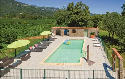 a swimming pool in a yard with chairs and umbrellas at Awesome Home In Santa Maria Poggio in Santa-Maria-Poggio