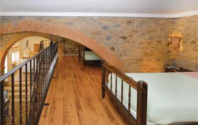 a room with a brick wall with a bed and a staircase at Amazing Home In Santa Maria Poggio in Santa-Maria-Poggio