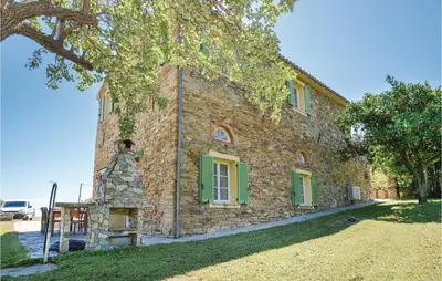 a large stone building with green shutters on it at Amazing Home In Santa Maria Poggio in Santa-Maria-Poggio