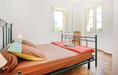 a bedroom with a bed with a metal frame and two windows at Beautiful Home In Santa Maria Poggio in Santa-Maria-Poggio