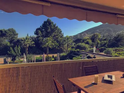 a wooden table on a balcony with a view of a mountain at Duplex vue mer in Sagone