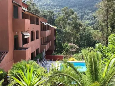 a building with a swimming pool next to a resort at Hotel Corsica - Porto Corse in Porto Ota