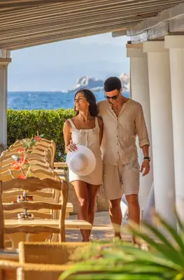 a man and a woman walking down a porch with a frisbee at Hotel & SPA des Pecheurs in Bonifacio