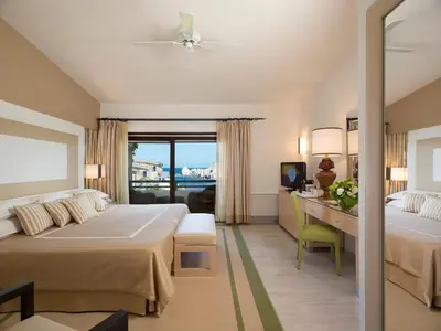 a hotel room with two beds and a desk at Hotel & SPA des Pecheurs in Bonifacio