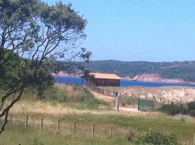 a field with a fence and a building and a body of water at Residence les Bell'ombres in Cargèse
