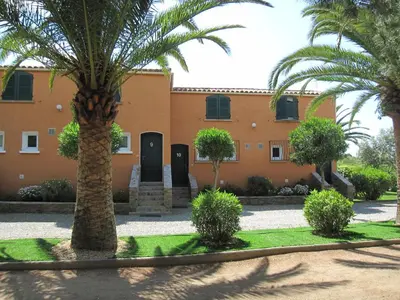 a building with palm trees in front of it at Residence les Bell'ombres in Cargèse