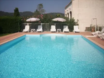 a large blue swimming pool with chairs and umbrellas at Residence les Bell'ombres in Cargèse