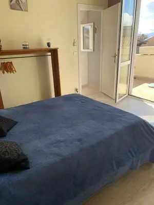 a bedroom with a large blue bed and a sliding glass door at Sables de biguglia cordon lagunaire in Borgo