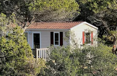 a small white house with a red roof at Camping Kévano Plage in Pianottoli-Caldarello