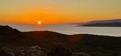 a sunset over a body of water with the sun setting at Camping Kévano Plage in Pianottoli-Caldarello