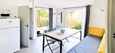 a kitchen and dining room with a table and a refrigerator at Camping Kévano Plage in Pianottoli-Caldarello