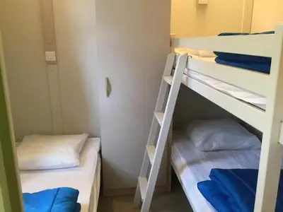 two bunk beds in a dorm room with blue pillows at Camping du Soleil in Appietto