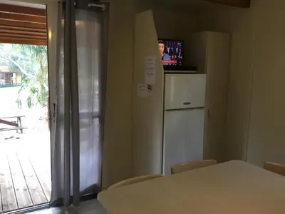 a kitchen with a table and a refrigerator and a window at Camping du Soleil in Appietto