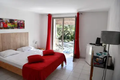 a bedroom with a bed with a red blanket and a window at Domaine Bocca di Feno in Bonifacio