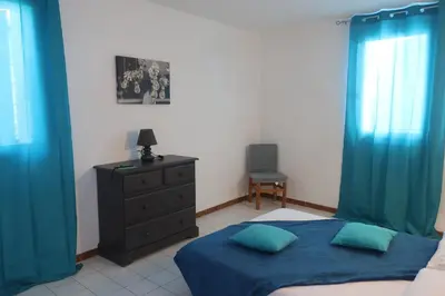 a bedroom with blue curtains and a bed and a dresser at Domaine Bocca di Feno in Bonifacio
