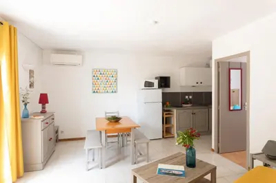 a living room with a table and a kitchen at Domaine Bocca di Feno in Bonifacio