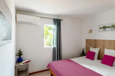 a bedroom with a bed with pink sheets and a window at Domaine Bocca di Feno in Bonifacio