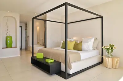 a bedroom with a canopy bed and a bathroom at Hôtel Cala di Greco in Bonifacio
