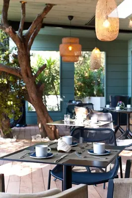 a table with chairs and coffee cups on a patio at Hôtel Cala di Greco in Bonifacio
