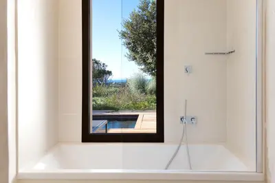 a bathroom with a bath tub with a window at Hôtel Cala di Greco in Bonifacio