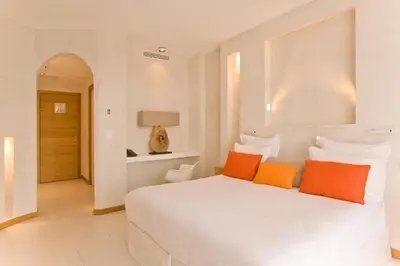 a bedroom with a white bed with orange pillows at Hôtel Cala di Greco in Bonifacio