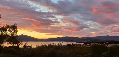 a sunset over a body of water with mountains at Vista Mare in Porticcio
